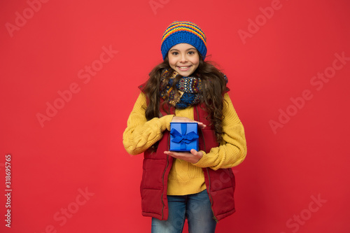 winter girl with new year present box. happy winter holidays. small girl knitted hat and scarf. ready for christmas. she is going on xmas party. seasonal shopping sales. childhood happiness