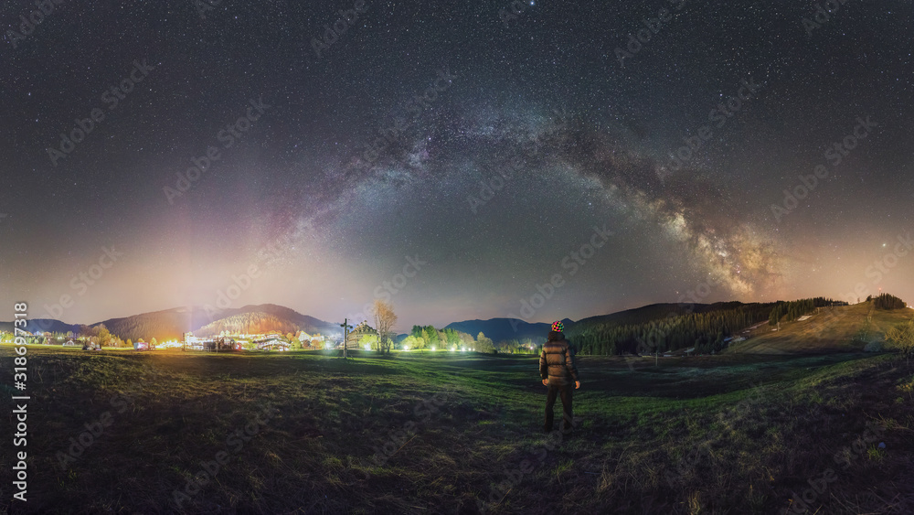 Person looks at the night sky with a milky way near the city