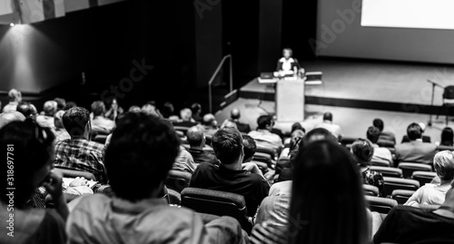 Speaker giving a talk in conference hall at business event. Audience at the conference hall. Business and Entrepreneurship concept. Focus on unrecognizable people in audience. Black and white image.