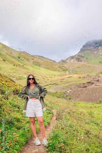 Beautiful happy young woman in mountains in the background of fog