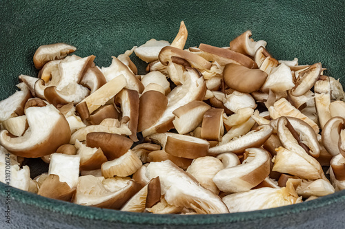 Chopped fresh oyster mushrooms in a cast iron pan with a non-stick coating close-up. Pleurotus ostreatus mushroom