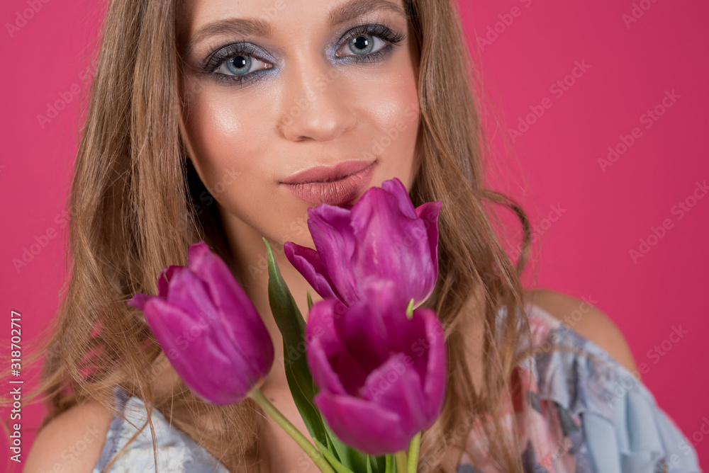 Close up portrait of smiling young woman enjoying the aroma of pink flowers. Isolated on pink background Close up portrait of smiling young woman enjoying the aroma of pink flowers. Isolated on pink background
