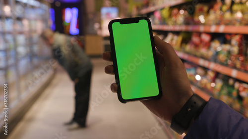 Lviv, Ukraine - May 19, 2018: On shop man hands holding use touch phone with horizontal green screen background busy finger touch message cellphone display girl slow motion