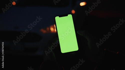 Lviv, Ukraine - May 19, 2018: On dark man hands holding use touch phone with vertical green screen street background sunset busy finger touch message cellphone display girl slow motion