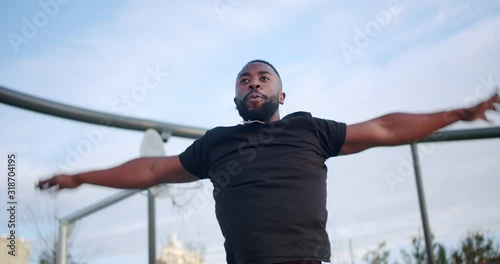 Strong healthy African man exercising and getting tired at early day in black sportswear, fast intense jogging on spot at sport ground endurance motivation of weight losing process fitness outdoor