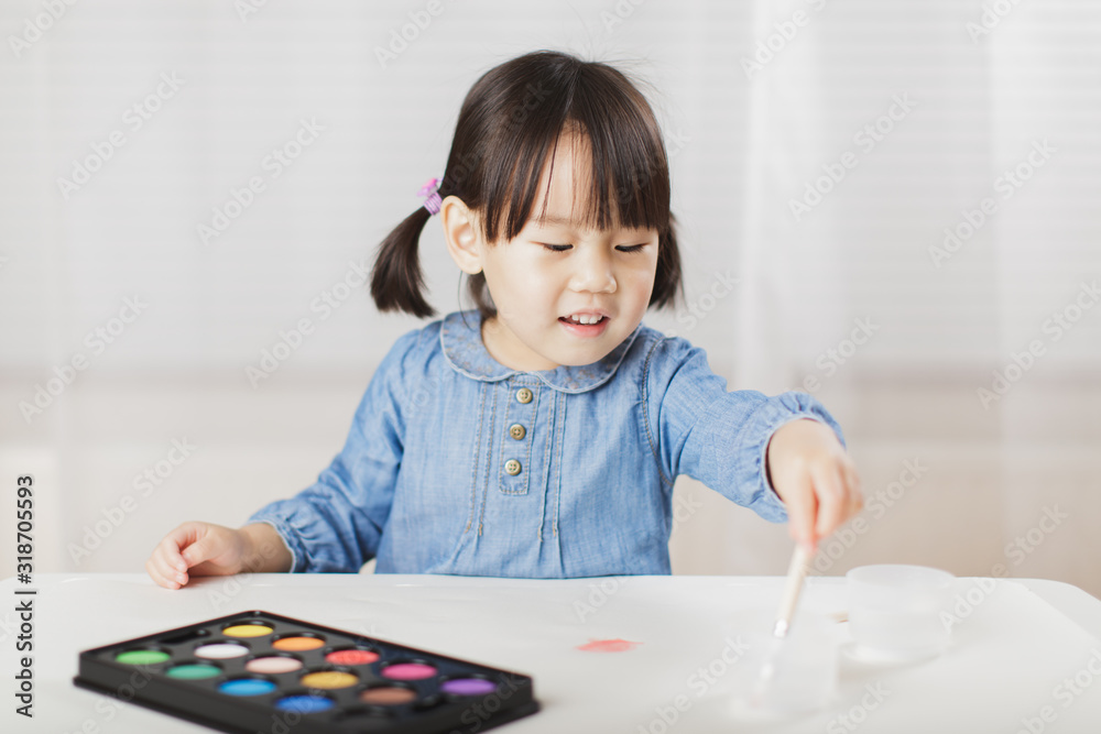 toddler girl practice watercolor paiting at home agianst white background