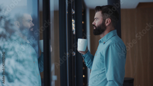 Obraz na plátně Close up young handsome man bearded drinking coffee and enjoying view from windo