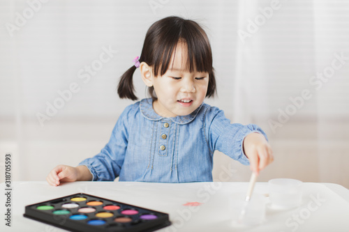 toddler girl practice watercolor paiting at home agianst white background