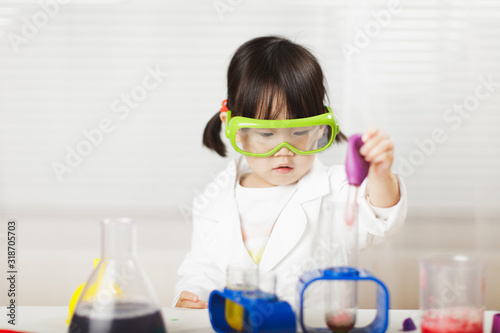 toddler girl pretend play  scientist  role  at home against white background