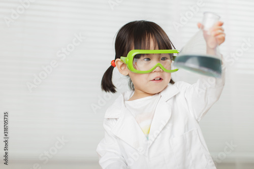 toddler girl pretend play scientist role at home against white background