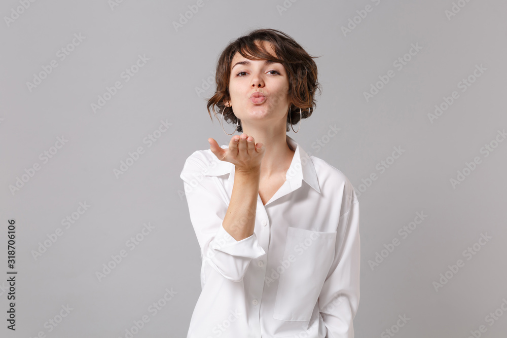 Charming pretty young business woman in white shirt posing isolated on grey wall background studio portrait. Achievement career wealth business concept. Mock up copy space. Blowing sending air kiss. Charming pretty young business woman in white shirt posing isolated on grey wall background studio portrait. Achievement career wealth business concept. Mock up copy space. Blowing sending air kiss.