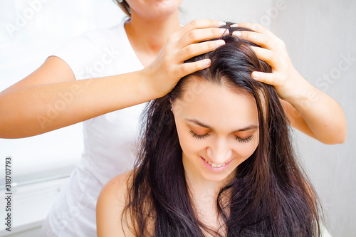 Masseur makes head massage to a young brunette woman. Head massage close up.