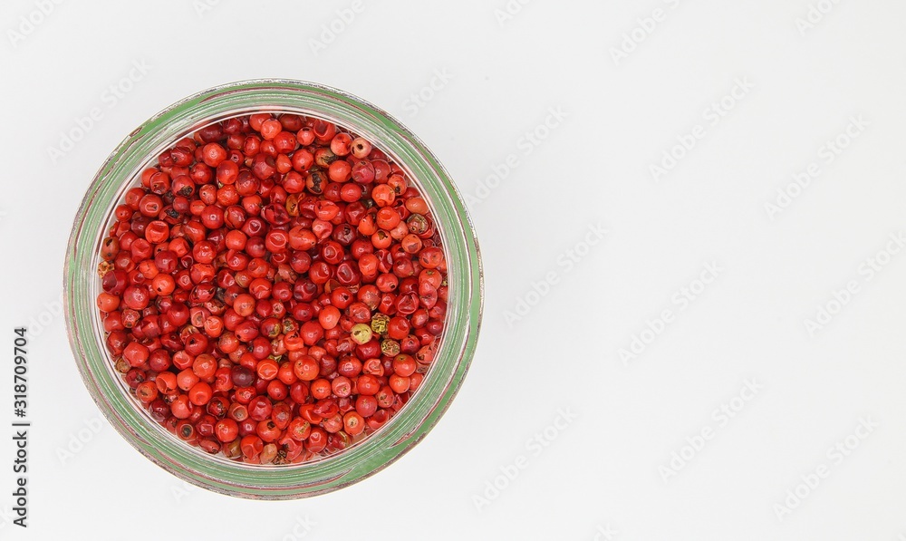 Top view on opening of isolated glass jar with red pepper corns and white blank empty background Top view on opening of isolated glass jar with red pepper corns and white blank empty background