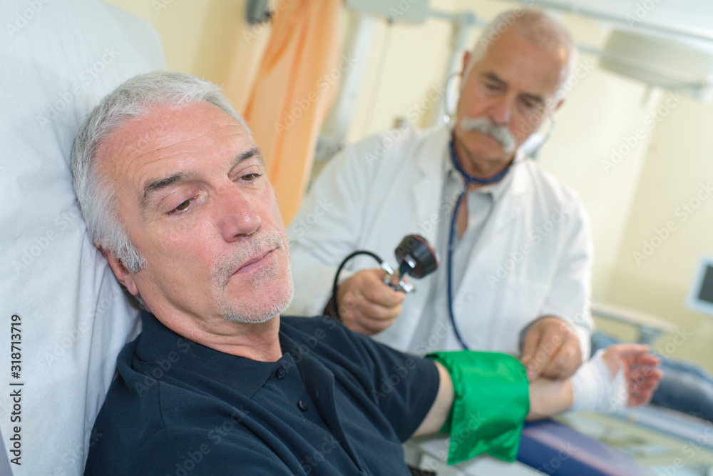doctor checking senior mans blood pressure in hospital doctor checking senior mans blood pressure in hospital