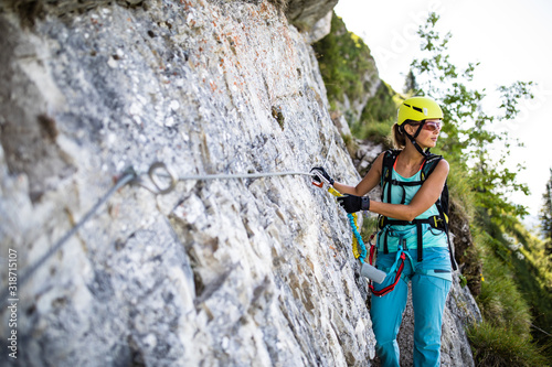 Pretty, female climber on a via ferrata -  climbing on a rock in Swiss Alps photo