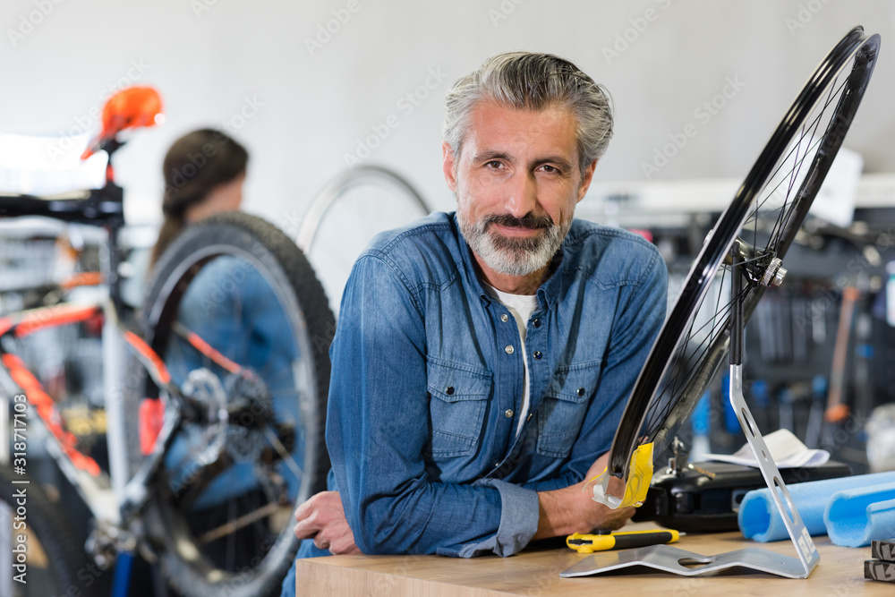 portrait of smiling man working in bike rental shop portrait of smiling man working in bike rental shop