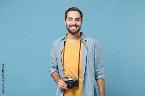 Traveler tourist man in yellow summer casual clothes with photo camera on neck isolated on blue background. Male passenger traveling abroad to travel on weekends getaway. Air flight journey concept.