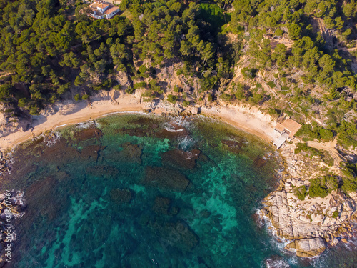 Aerial top view of coastal with cliff, turquoise water, rocks, foam, waves, and trees