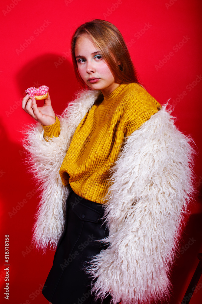 little cute blond teenage girl posing in fashion style with donut on red background, lifestyle people concept little cute blond teenage girl posing in fashion style with donut on red background, lifestyle people concept