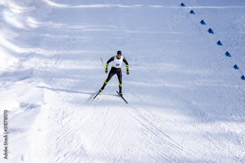 A man cross-country skiing race on the trail. Man in modern ski running clothes with number on chest