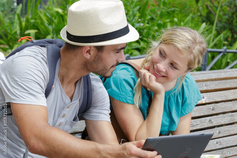 young couple sitting on beach using tablet young couple sitting on beach using tablet