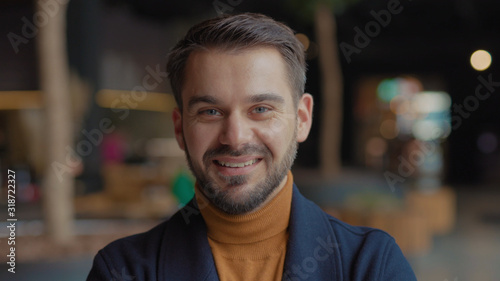 Young smiling portrait face young attractive man look at camera successful lifestyle achievement cheerful casual in office indoors close up slow motion