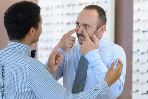 customer talking to optician and pointing to his nose