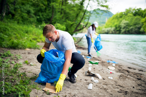 фотографія Young group of volunteers cleaning garbage on river shore