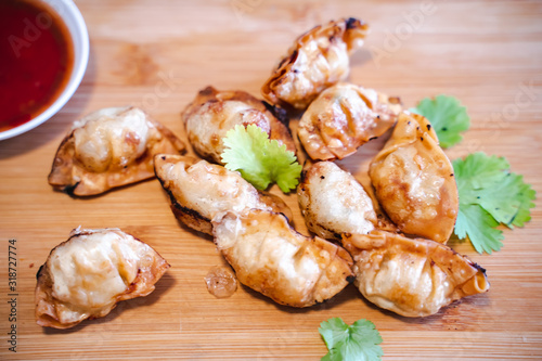Crispy deep-fried wontons on wooden plate serve with sweet chilli sauce.