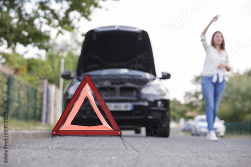 woman by broken down car hailing help