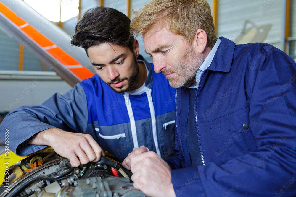 two mechanics working on a car two mechanics working on a car