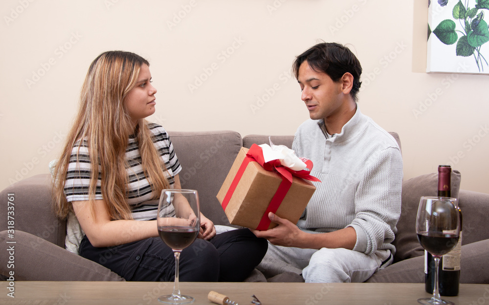 Cute young latin couple exchanging gift for valentines day Cute young latin couple exchanging gift for valentines day