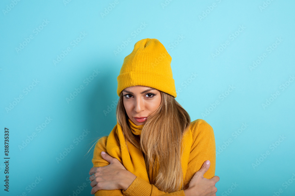 Girl covers herself to avoid catching a cold. Cyan background