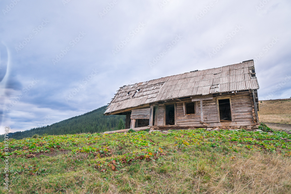 Old settlement in the mountains among the pastures with dried grass and fir-trees forest on the background. Old settlement in the mountains among the pastures with dried grass and fir-trees forest on the background.