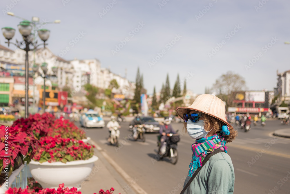 Caucasian woman wearing sanitary mask outdoors in Da Lat city centre Vietnam. Tourist with medical mask protection against risk of chinese corona virus epidemy in Asia. Anti smog mask pollution.