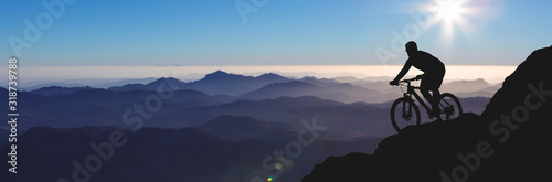 Conquering mountain peaks by cyclist in shorts and jersey on a modern carbon hardtail bike with an air suspension fork . Beautiful view from the mountain. Panoramic view for banner.