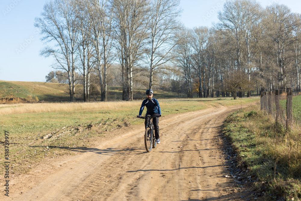 Cyclist in pants and fleece jacket on a modern carbon hardtail bike with an air suspension fork rides off-road.