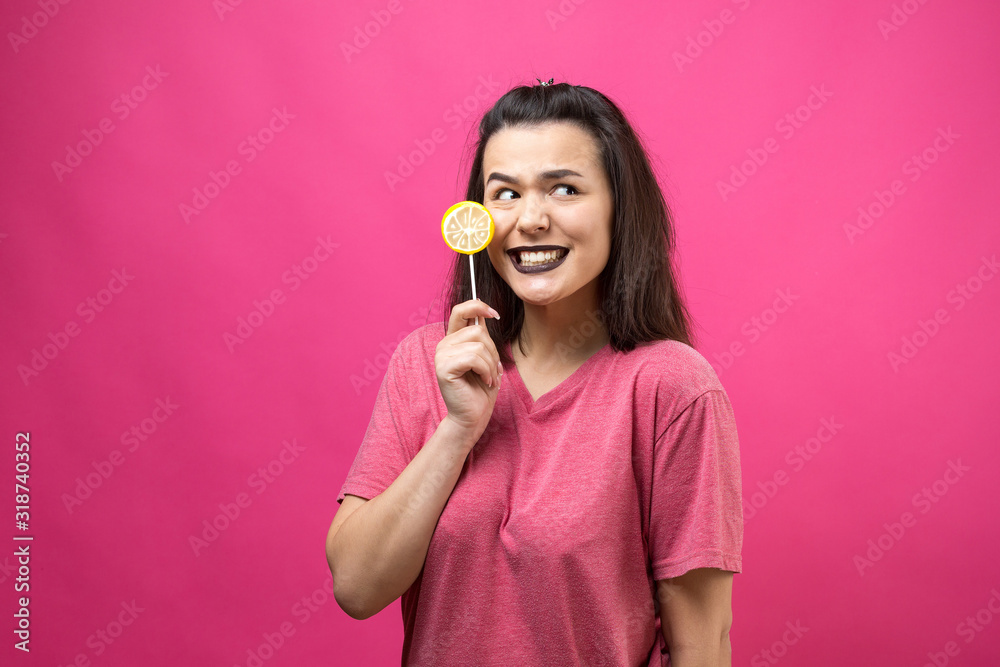 Portrait of lovely sweet beautiful cheerful woman with straight brown hair holding a lollipop near the eyes. Portrait of lovely sweet beautiful cheerful woman with straight brown hair holding a lollipop near the eyes.