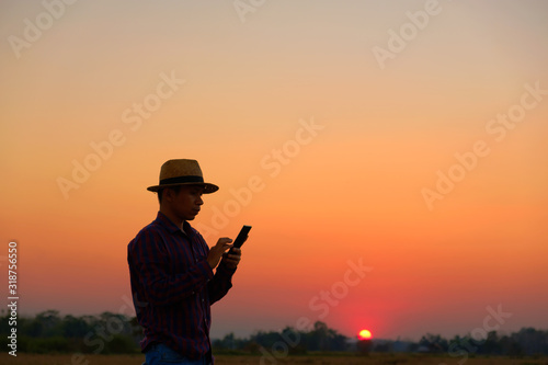 Men wearing striped shirts with a straw hat stand to use the phone At sunset with copy space