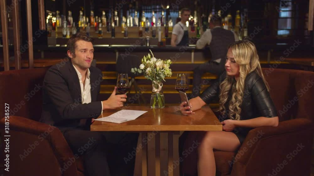 Man drinks alcohol and looks at his woman who talks via video link Man drinks alcohol and looks at his woman who talks via video link