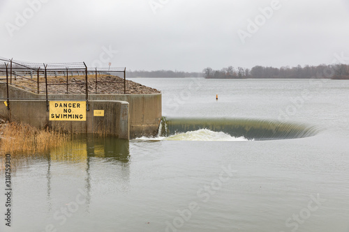 фотографія Water flowing over bell-mouth spillway dam after winter storms brought heavy rain and flooding