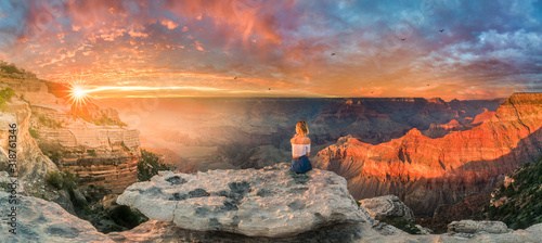 Young woman sitting on the edge of rim and enjoying the Grand Canyon sunset