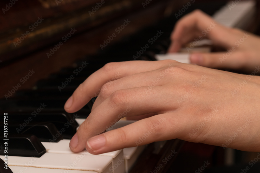 Fototapeta premium Hands of a girl playing the piano close-up