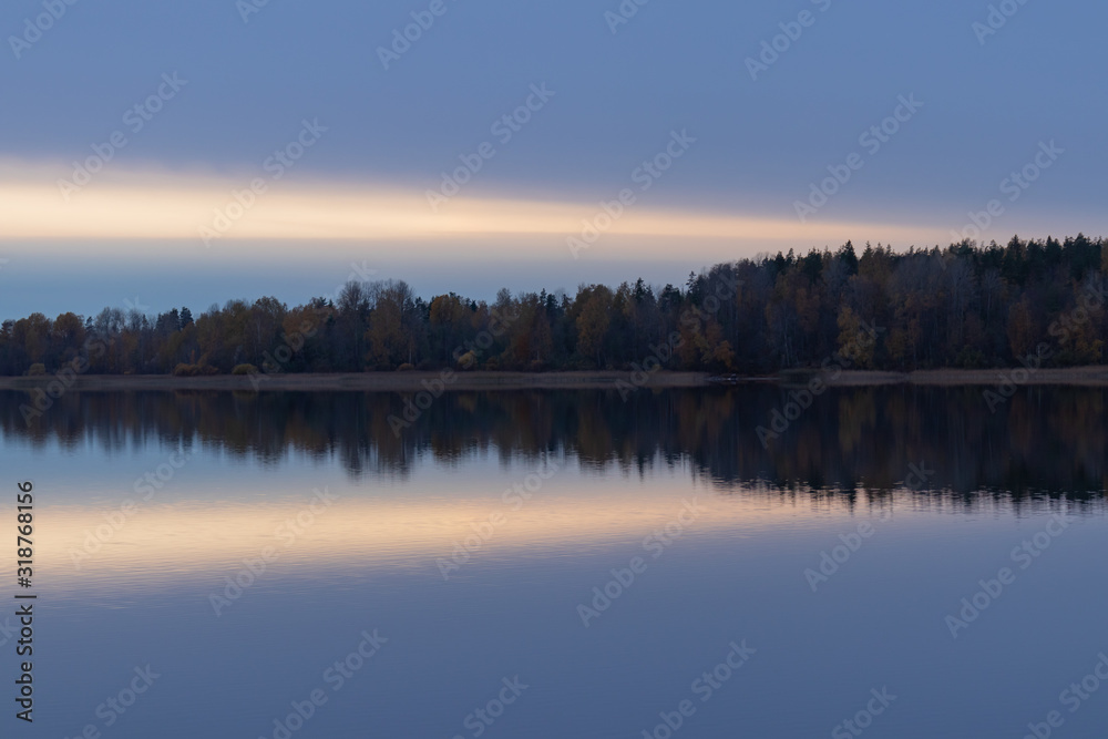 Serene landscape. Sunset on the lake, calm water surface, symmetrical reflection