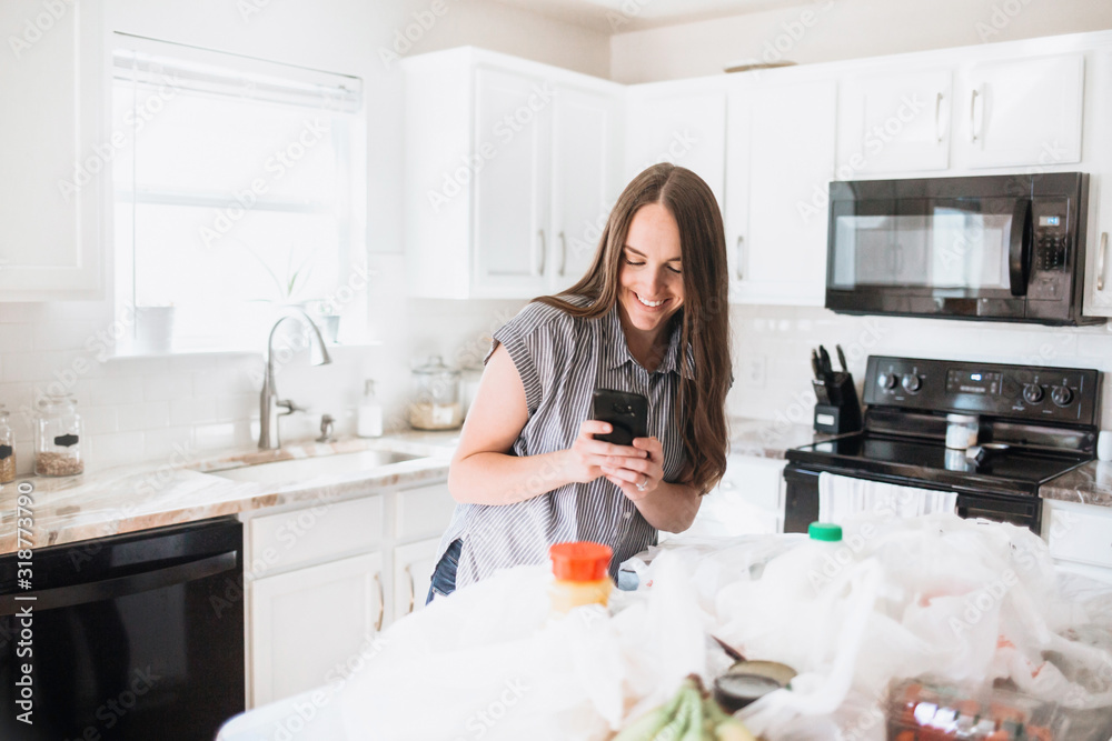 Lifestyle of women unloading her groceries at home in a white kitchen Lifestyle of women unloading her groceries at home in a white kitchen