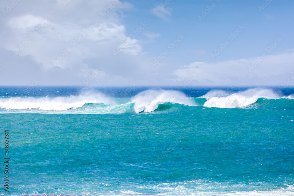 Naklejka premium Crushing waves in the sea under blue sky with white clouds