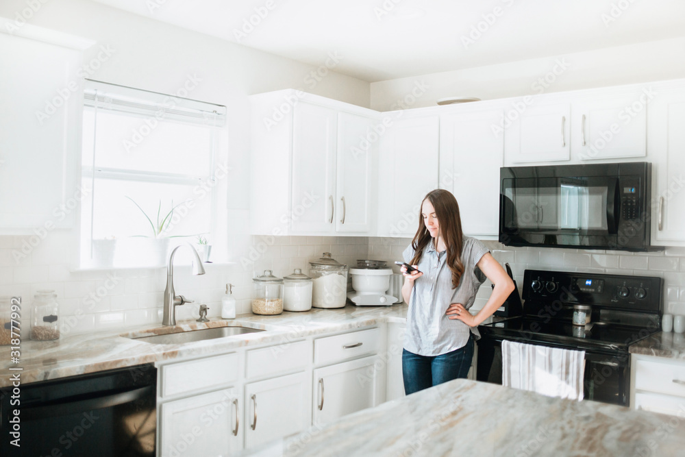 Lifestyle of Women using Cell Phone in White Kitchen Lifestyle of Women using Cell Phone in White Kitchen