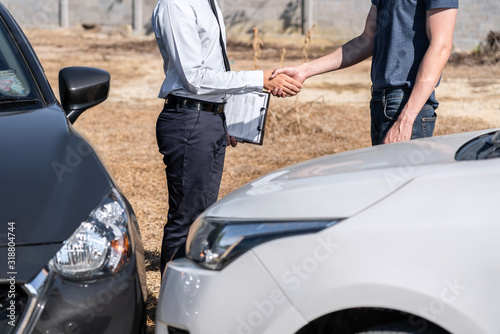 Insurance Agent and customer shaking hands after agreement about in insurance claim, assessed examining car crash, checking and signing on report claim form process after accident collision