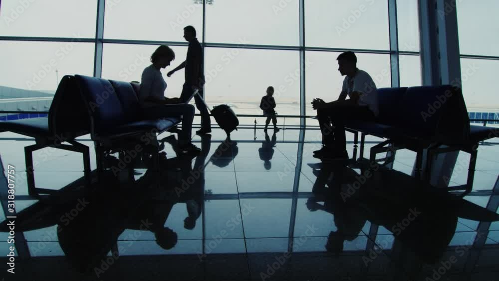 People in the airport terminal use devices, hurry to their flight