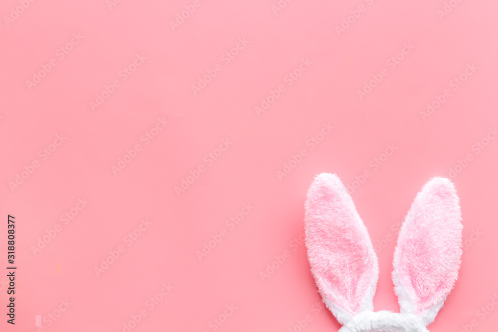 Easter bunny concept. Toy rabbit's ears on pink background top-down copy space